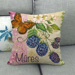 Linen cushion cover with orange butterfly, flowers and blackberries on a gray sofa