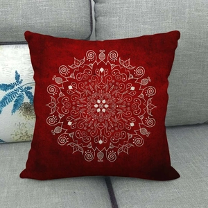 Housse de coussin en lin rouge avec motif mandala blanc sur un canapé gris moderne