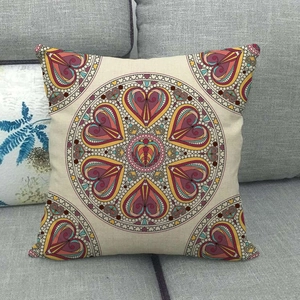 Linen decorative throw pillow with colorful geometric mandala pattern on a gray sofa