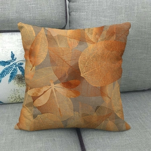Detail view of linen pillowcase with autumn maple leaves and dragonfly print on grey sofa