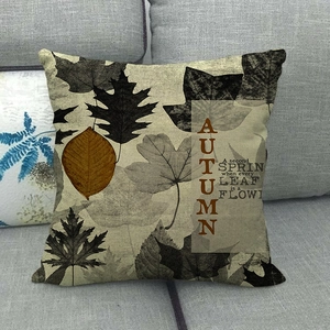 Detail of autumn linen pillowcase with maple leaves and 'AUTUMN' quote on gray sofa