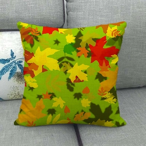 Detail of fall maple leaf print on linen pillowcase shown on a grey fabric sofa