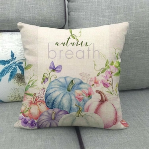 Watercolor pumpkin linen pillowcase featuring autumn breath print on a grey fabric sofa