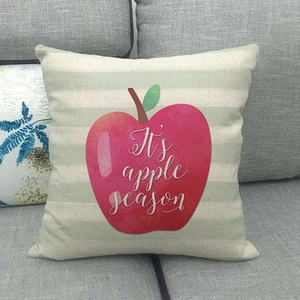Detail of linen cushion cover with stripes and red apple print and apple season text