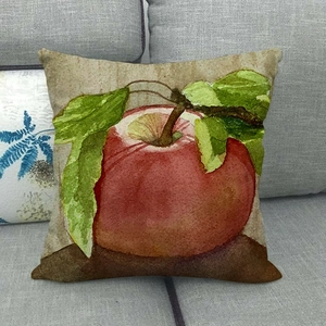 Linen pillowcase with watercolor red apple print on a gray fabric sofa setup