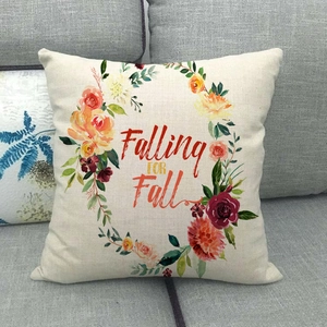 Close-up of linen pillow cover with Falling FOR Fall text on a grey fabric sofa