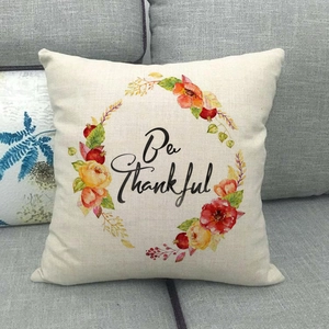 Close-up of linen pillowcase with watercolor floral wreath and Be Thankful text