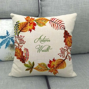 Close-up of linen pillowcase with autumn wreath design on a grey sofa setting