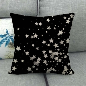 Black linen pillowcase with golden star pattern on grey fabric sofa background
