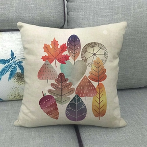 Close-up of linen cushion cover with colorful autumn maple leaf patterns on a grey sofa