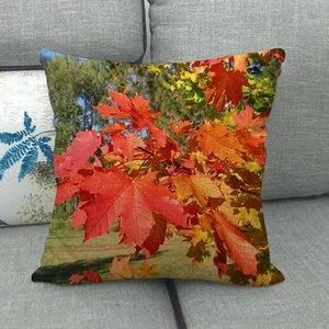 Close-up of linen pillowcase with autumn maple leaf print on a gray sofa