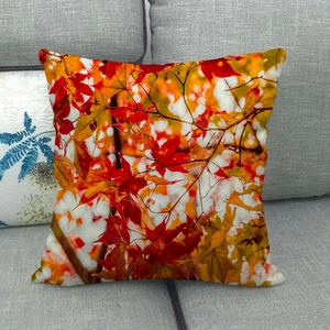 Close-up of fall maple leaf print on textured linen pillowcase on a grey sofa