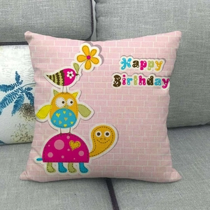 Detail of happy birthday linen cushion cover with cartoon owl and turtle on a sofa
