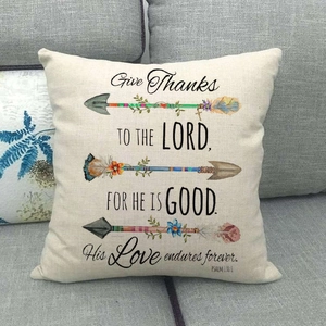 Linen pillowcase with arrow graphics and Psalm 136:1 verse on a gray sofa