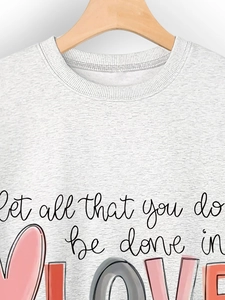 Close-up of heart print and 'Let all that you do be done in LOVE' text on grey sweatshirt