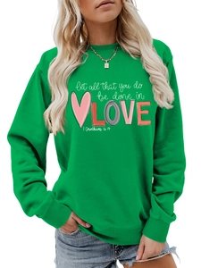 Detail of emerald green sweatshirt with 'Let all that you do be done in LOVE' printed text