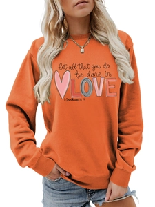 Close-up of the printed quote let all that you do be done in love on an orange sweatshirt