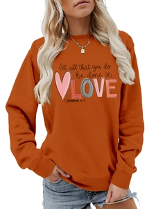 Detail of orange sweatshirt featuring Love typography and 1 Corinthians 16:14 script