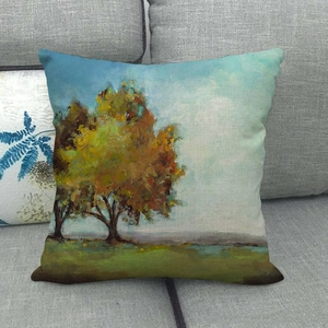 Detail of linen pillow cover featuring autumn landscape oil painting on a gray sofa