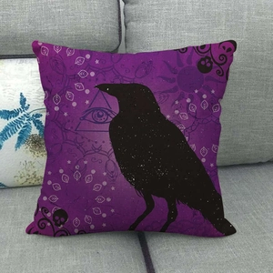 Halloween pillow cover featuring black raven and purple gothic eye motifs on a gray sofa