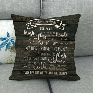 Linen throw pillow cover with rustic wood grain print and white Bathroom Rules typography