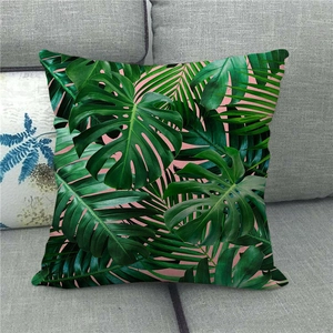 Detail of Monstera leaf print linen pillow cover on a grey sofa with tropical design