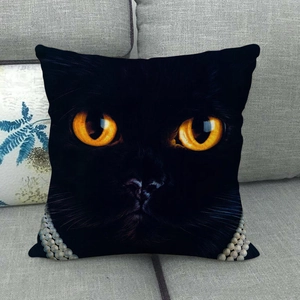 Detailed close-up of a black cat cushion with orange eyes and pearl necklace print