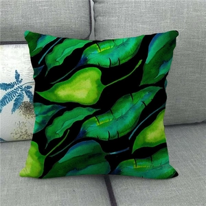 Detail of tropical green monstera leaf print on linen throw pillow cover on gray sofa