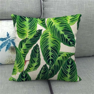 Detailed view of linen pillowcase with tropical monstera leaf print on a gray sofa