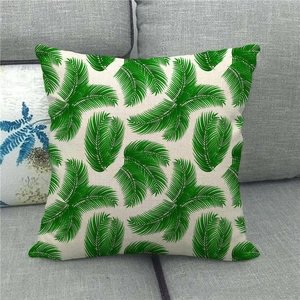 Close-up of linen pillowcase featuring vibrant green palm leaf print on a grey sofa
