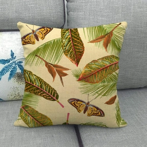 Detail of linen cushion cover featuring butterfly and tropical leaf patterns on a sofa