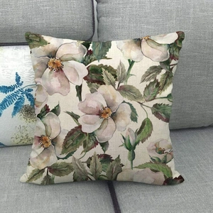 Linen throw pillow cover with vintage watercolor flowers on a modern grey sofa