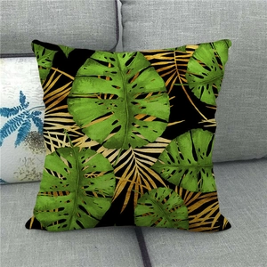 Detail of tropical monstera and gold palm leaf patterns on linen pillow cover