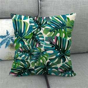 Linen pillowcase with tropical monstera leaves pattern displayed on a grey sofa