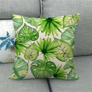 Close-up of tropical monstera leaf patterns on a textured linen pillowcase on a grey sofa