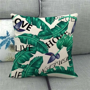 Close-up of linen pillowcase with green tropical leaves and decorative black text