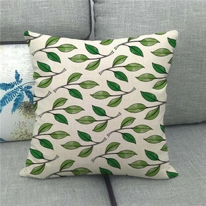 Close-up of square linen pillowcase featuring green monstera leaf patterns on a grey sofa