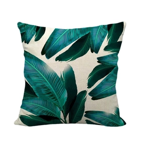 Linen cushion cover with tropical green leaf pattern on a neutral beige background