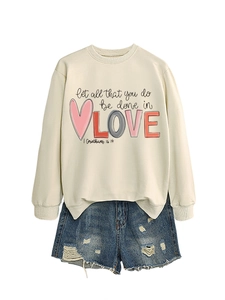 Detail of beige fleece sweatshirt with art text and blue distressed denim shorts set