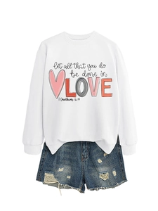 Detail of white crewneck sweatshirt with 'LOVE' graphic and denim shorts with frayed hems