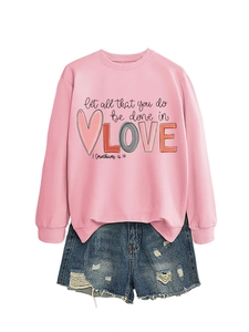 Flat lay of pink cotton sweatshirt with 'Let all that you do be done in LOVE' print text