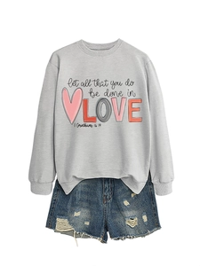 Flat lay of gray long sleeve sweatshirt with printed quote and distressed denim shorts