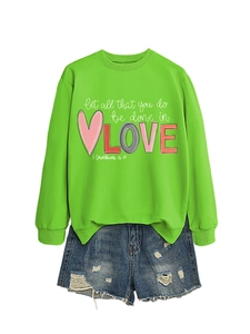 Detail of lime green sweatshirt featuring 'Let all that you do be done in LOVE' print