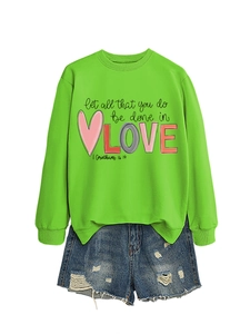 Detail of lime green sweatshirt with 'LOVE' typography and distressed denim shorts