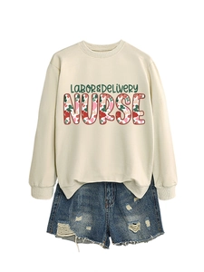 Detail view of beige labor and delivery nurse sweatshirt with floral pattern lettering