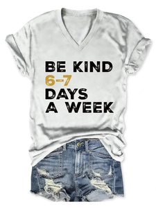 Detail of V-neck white t-shirt featuring Be Kind typography and distressed denim shorts
