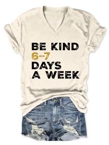 Flat lay of Be Kind V-neck short sleeve tee paired with distressed denim shorts