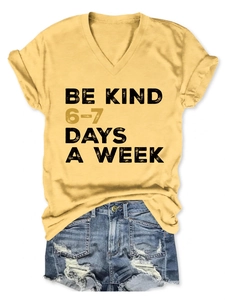 Close-up of yellow V-neck cotton T-shirt with Be Kind print and frayed denim shorts