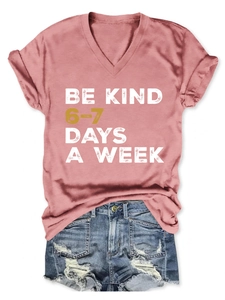 Detailed view of the pink V-neck T-shirt featuring Be Kind 6-7 Days A Week text print