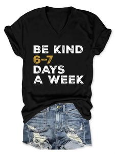 Detail of Be Kind graphic on black V-neck t-shirt and distressed blue denim shorts